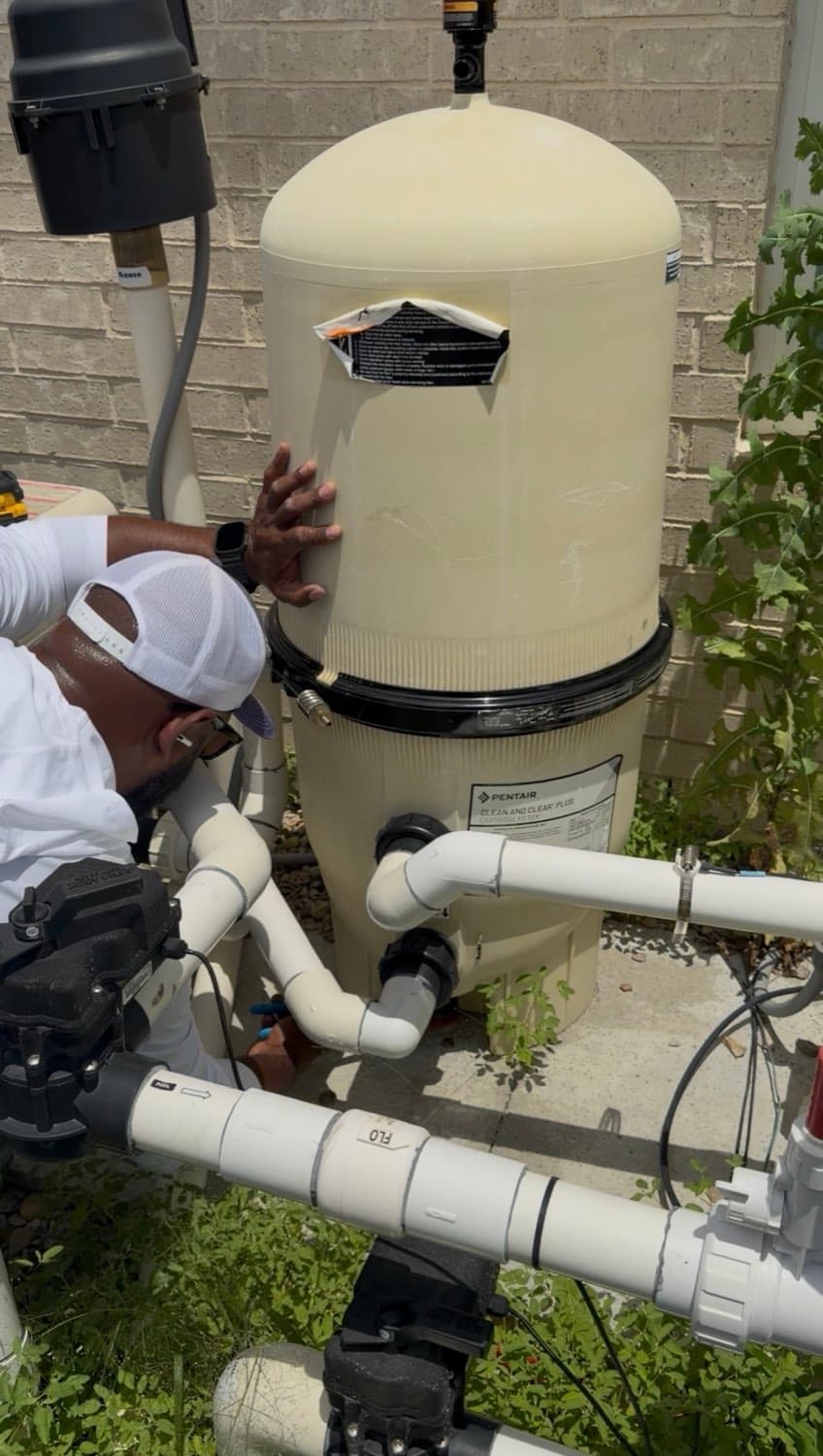 A Purple Frog Pools technician servicing a pool filter tank at a backyard equipment pad